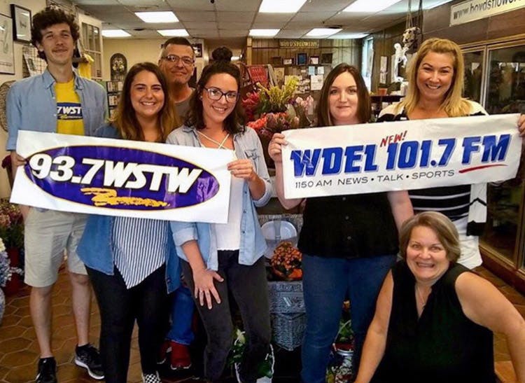 Members of the Boyd's team, posing with banners from several local radio stations