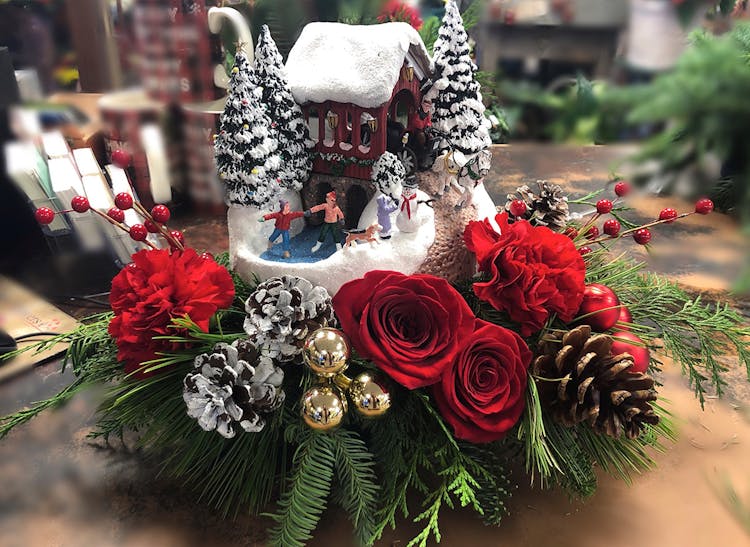 A winter-themed gift, dressed with red roses, pine cones and holly